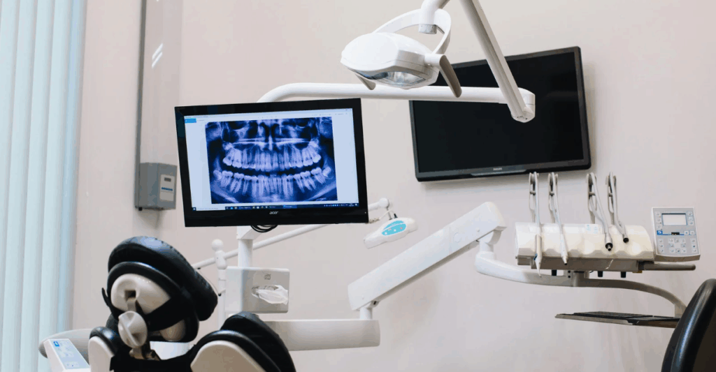 (Modern dental office with a digital X-ray image displayed on a screen beside the patient chair.)